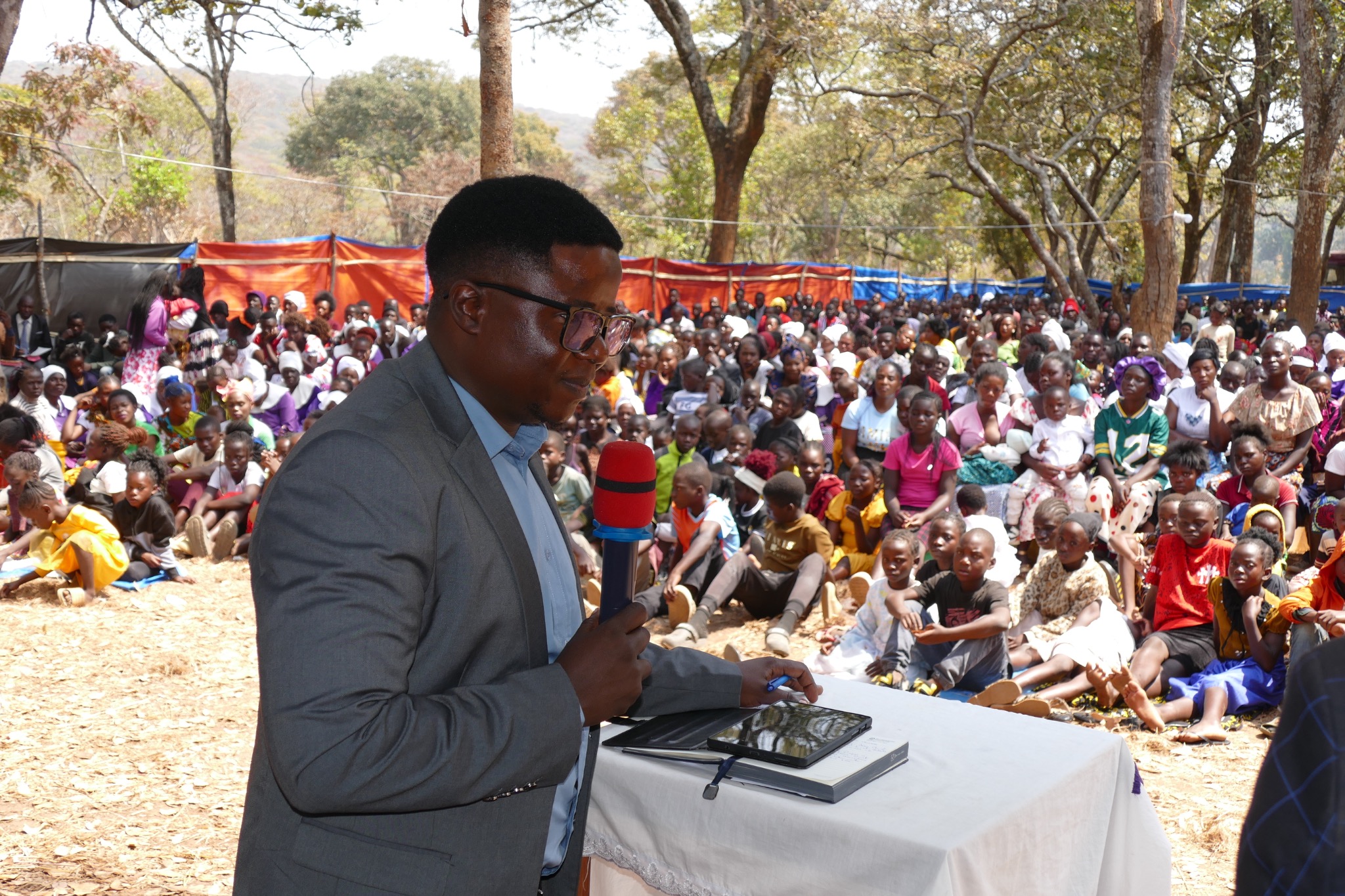 Michael Mumanga speaking to a large outdoor gathering in Zambia